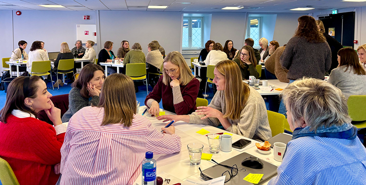 Personer som sitter rundt flere gruppebord